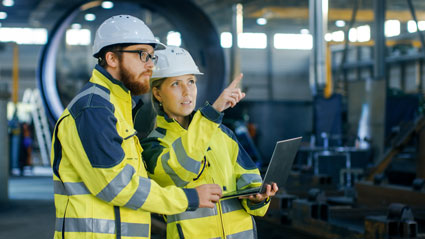 Produktion: Mann und Frau mit Laptop in einer Produktionshalle