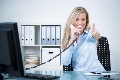 Büromitarbeiterin am Telefon mit Daumen hoch.