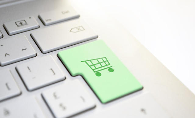 Ausschnitt einer Computertastatur mit grünem Einkaufswagensymbol auf der Enter-Taste