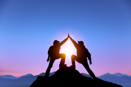 Zwei Erfolgspartner, auf einem Berggipfel angelangt, gratulieren einander mit "high five".